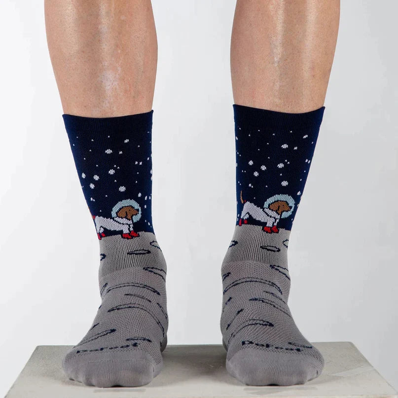 A pair of legs wearing DeFeet Aireator 6" Moon Doggo cycling socks in navy and gray with astronaut dog in space on the cuff.  
