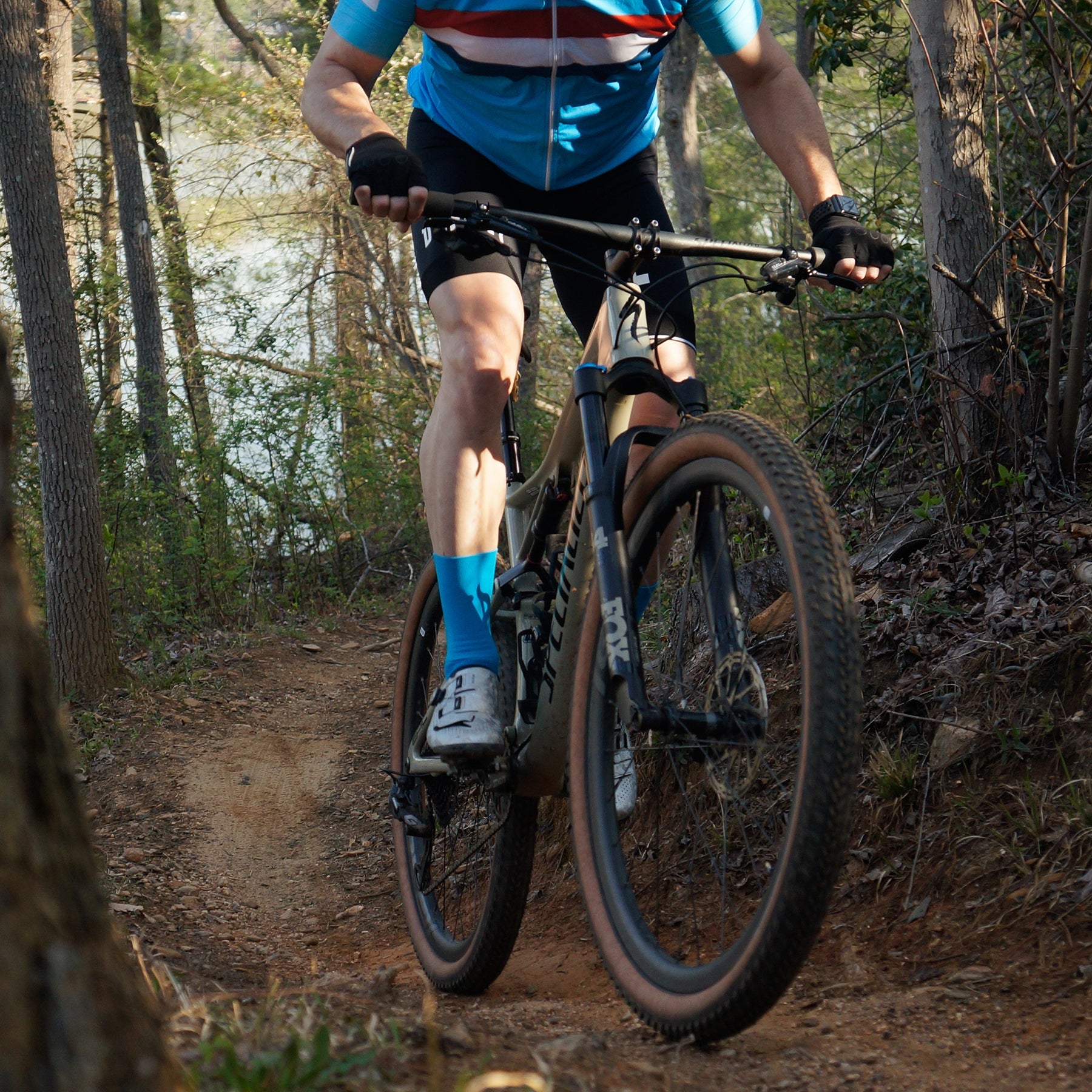 male cyclist on a trail wearing blue DeFeet Aireator cycling socks
