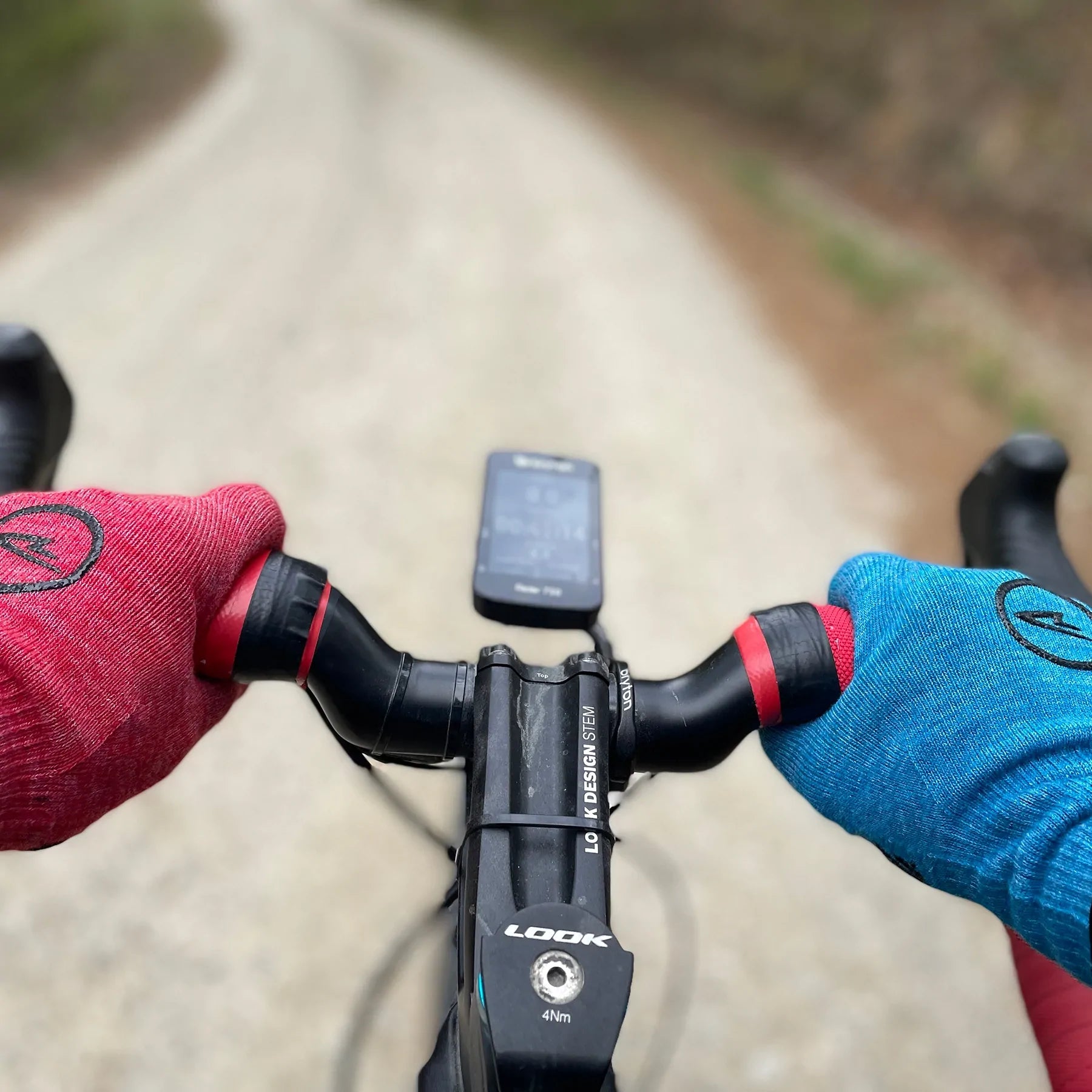 man riding bike with hands on handlebars wearing Merino wool DeFeet cycling gloves in red and blue